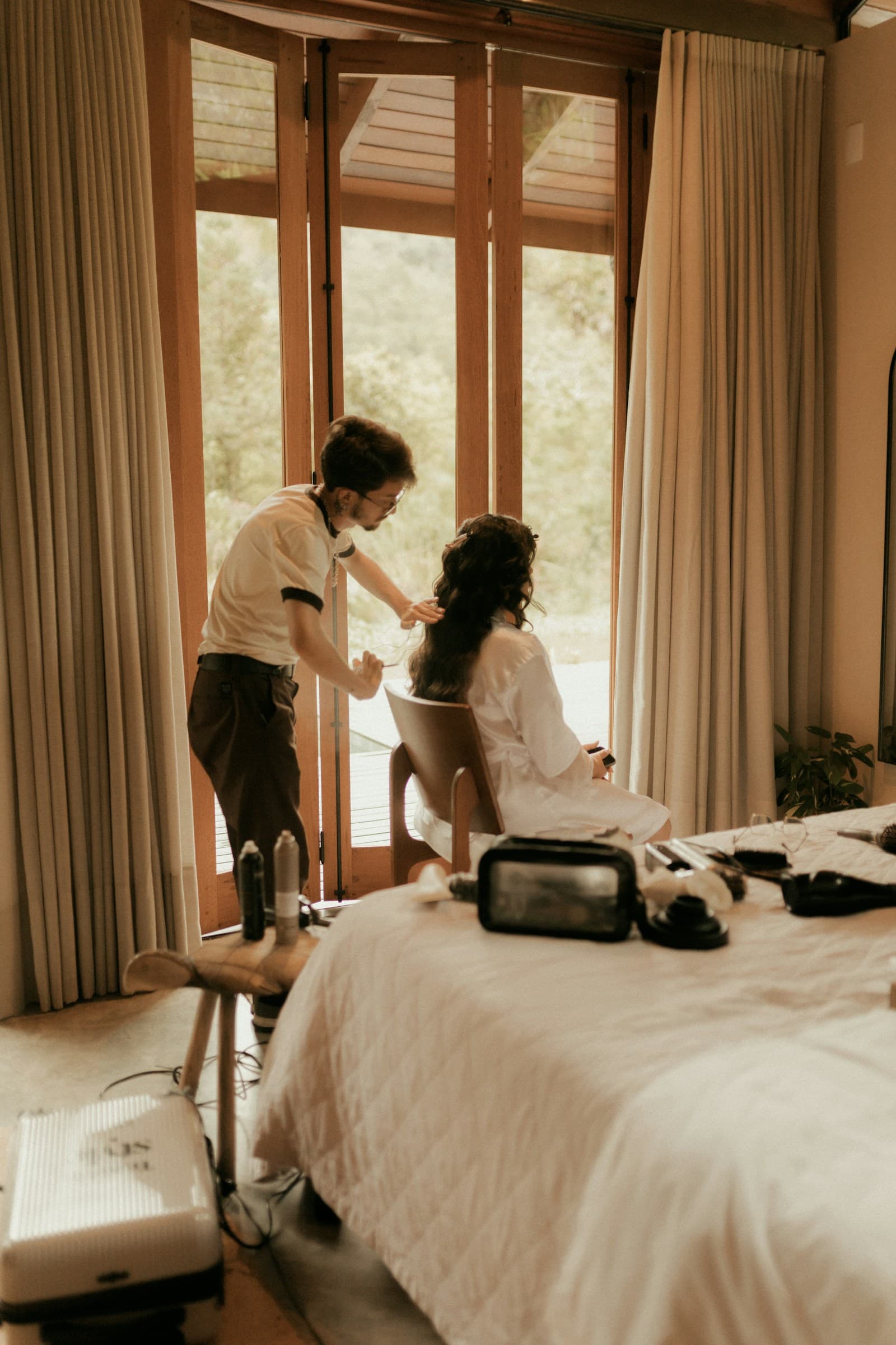 Stylist tending to a client’s hair in warm window light